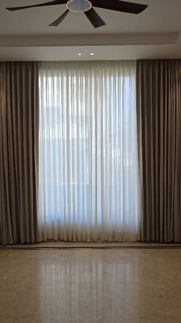Layered sheer and blackout curtains installed in a bedroom